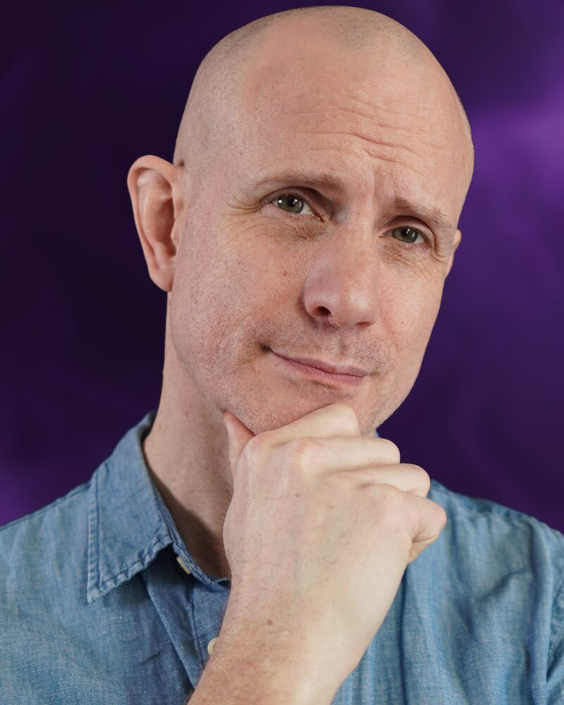Mickey Mullin, chin on hand, in a blue chambray shirt