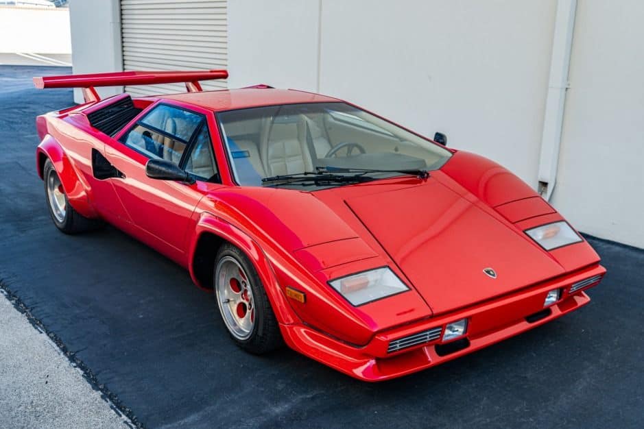 Red Lamborghini Countach parked in the shade of a building.