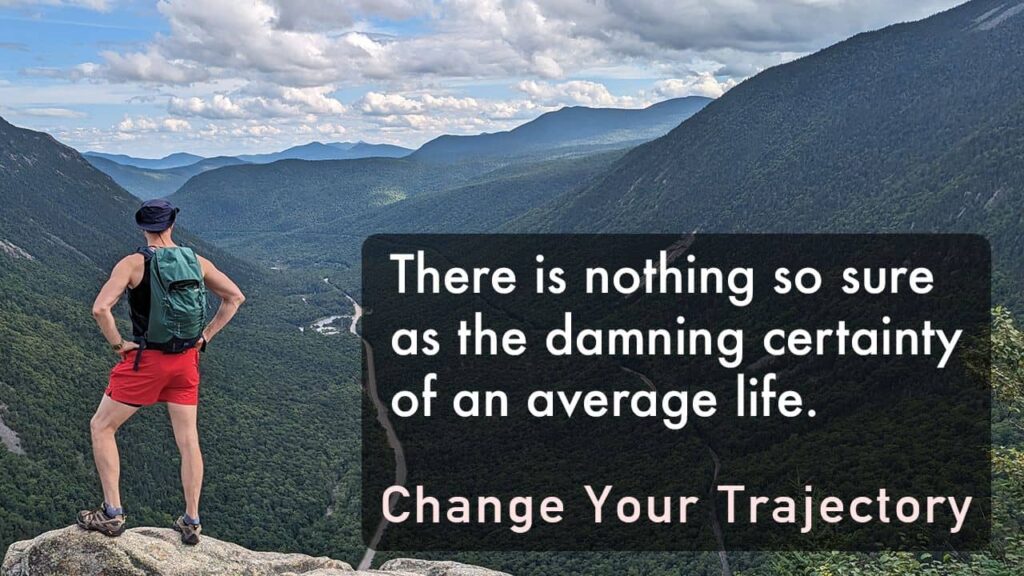 Mickey in red shorts and navy tanktop, wearing backpack, looking out over valley. Text overlay: "There is nothing so sure as the damning certainty of an average life. Change Your Trajectory"